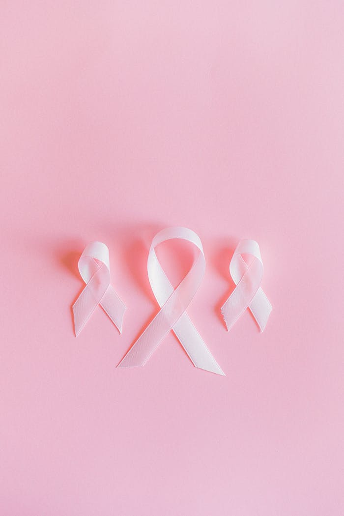 Three pink ribbons symbolize breast cancer awareness on a light pink background.